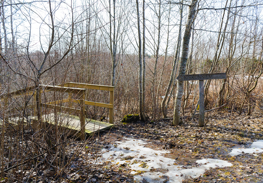 Retkeilyreitin opastekyltti osoittaa puisiin portaisiin. Ympärillä on metsää.