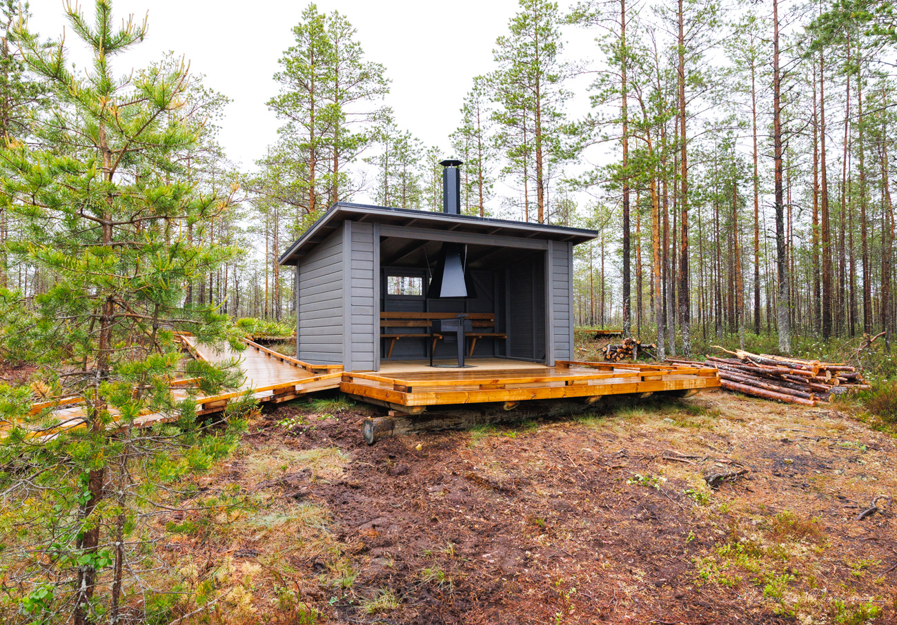 Laavu metsän keskellä. Laavun edessä on puinen tasanne.